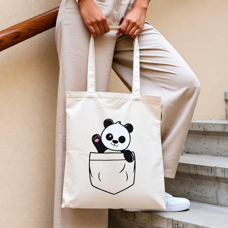 Cream tote bag with a cartoon panda peeking out of an illustrated pocket.