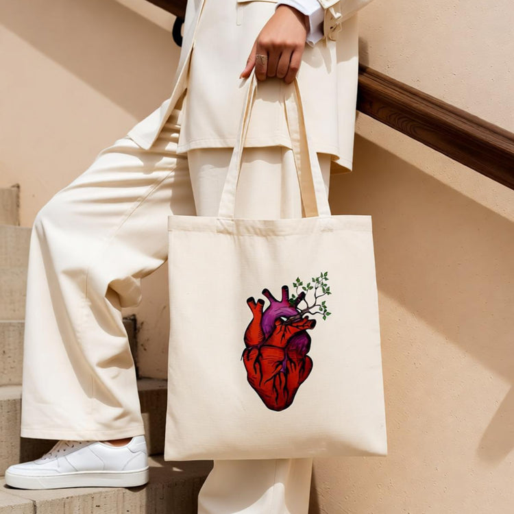 Cream tote bag with an anatomical heart and botanical illustration.