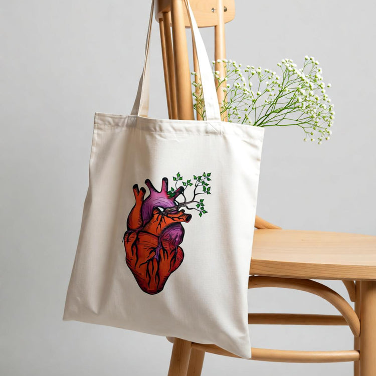 Cream tote bag with an anatomical heart and botanical illustration.
