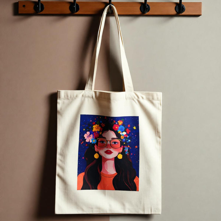Cream tote bag with a colourful illustrated woman's portrait on a dark background.