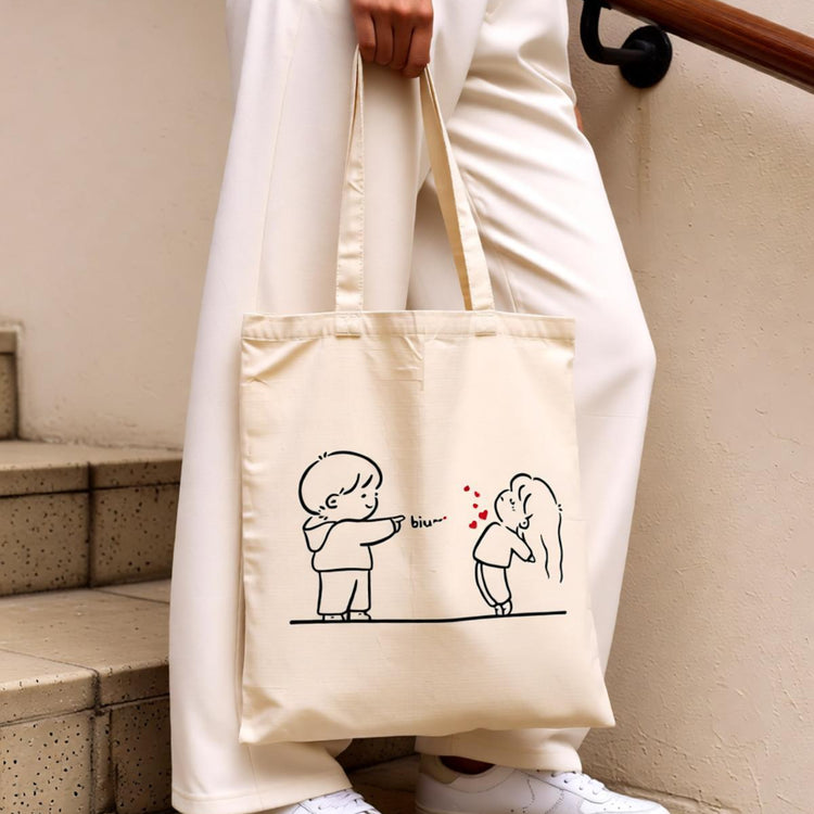 Cream tote bag with a simple line drawing of two people exchanging a heart.