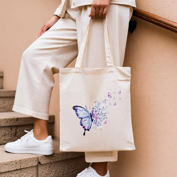 Cream tote bag with a blue butterfly and delicate floral trail.