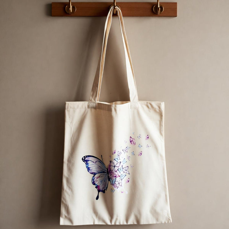 Cream tote bag with a blue butterfly and delicate floral trail.