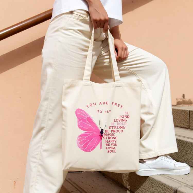 Cream tote bag with a pink butterfly and motivational lettering.