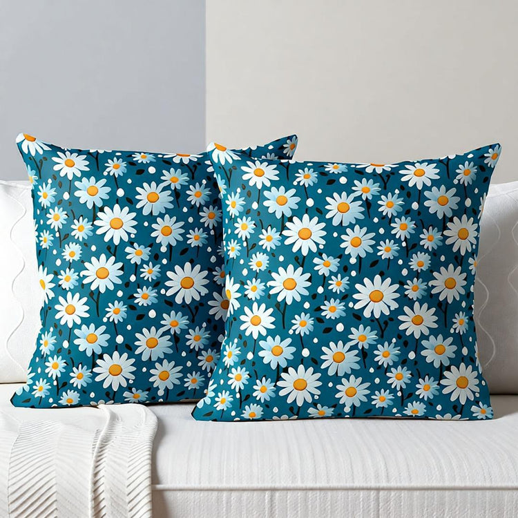 Two teal cushion covers with a dense white daisy print on a sofa.