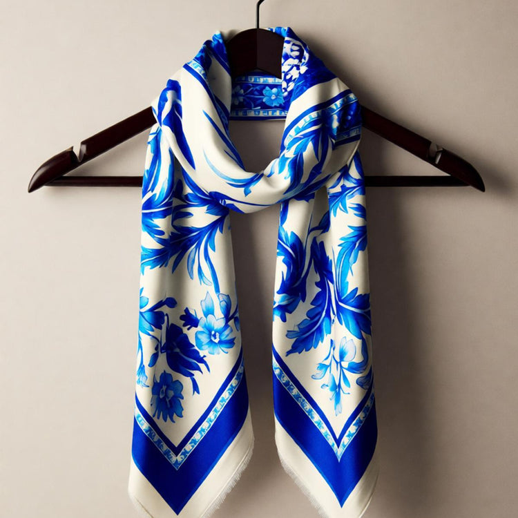 Blue and white floral scarf displayed on a dark hanger.