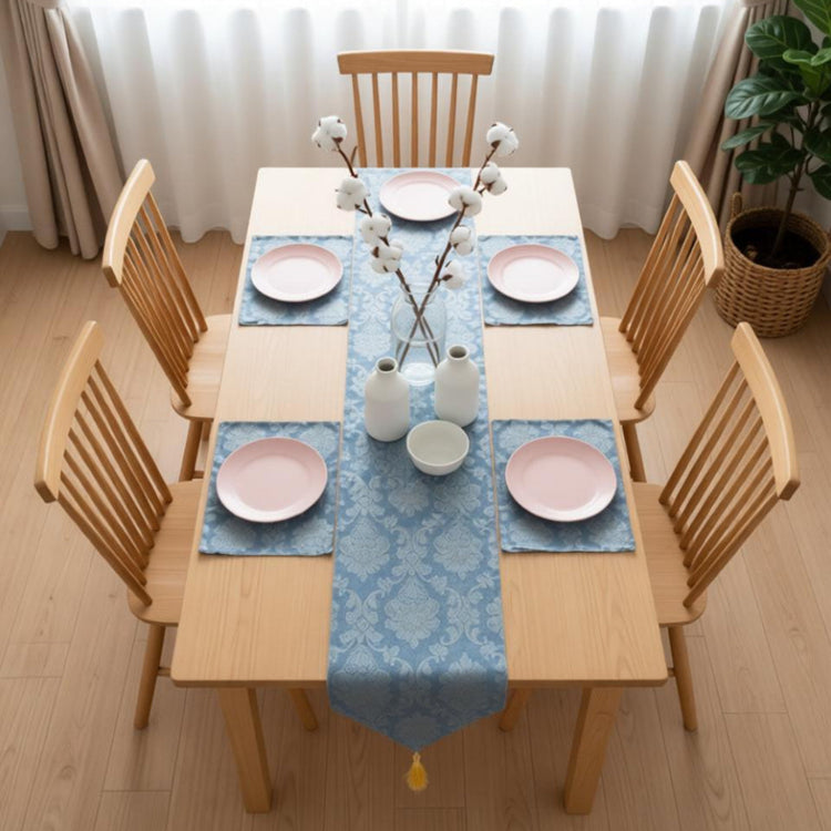Blue ornamental table runner with matching placemats on a dining table.