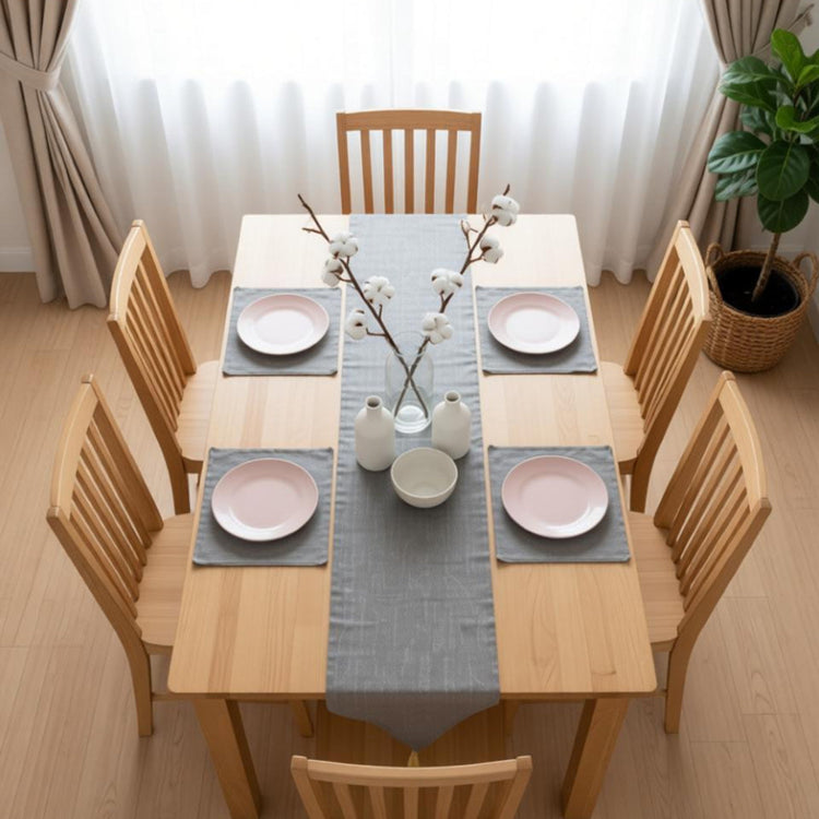 Grey table runner with matching placemats beneath pink plates.