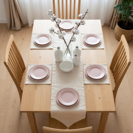 Plain cream table runner with matching placemats on a dining table.