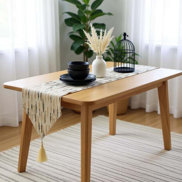 Cream table runner with grey and gold motifs draped over a wooden table.