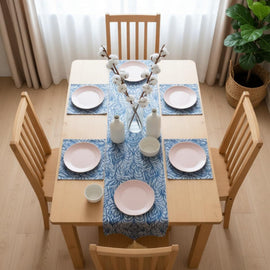 Blue ornamental table runner with matching placemats on a wooden dining table.