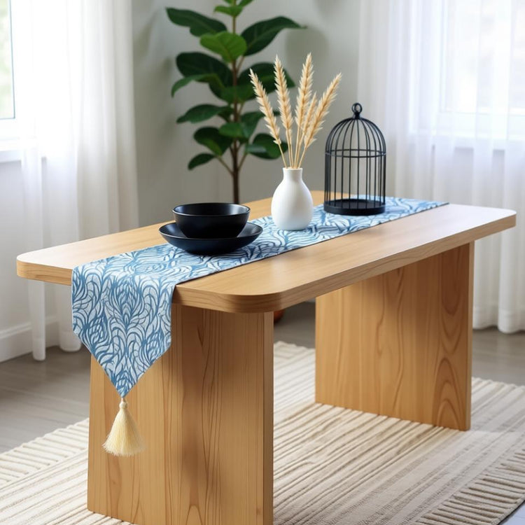 Blue ornamental table runner with a pointed tasselled end on a wooden table.