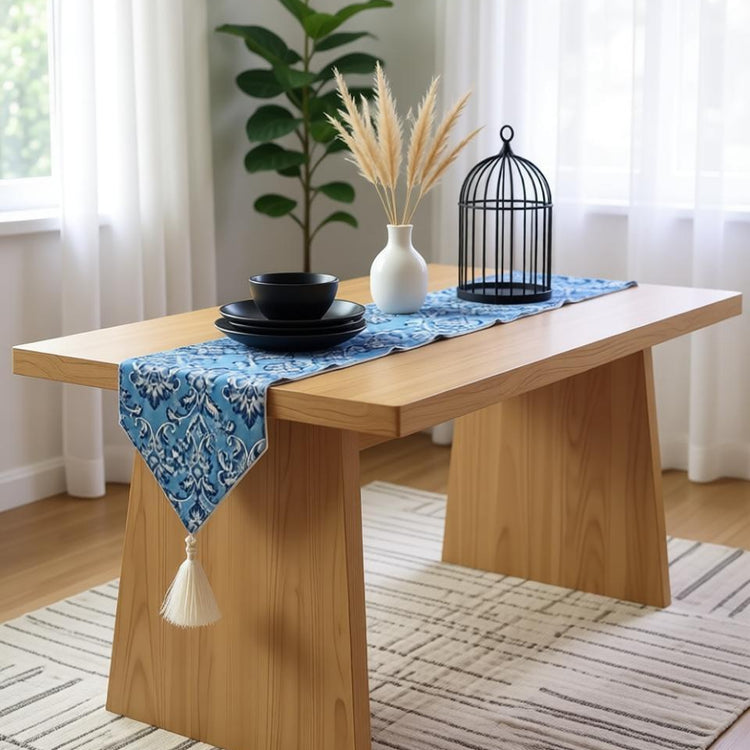 Blue damask table runner with a pointed end and a cream tassel.