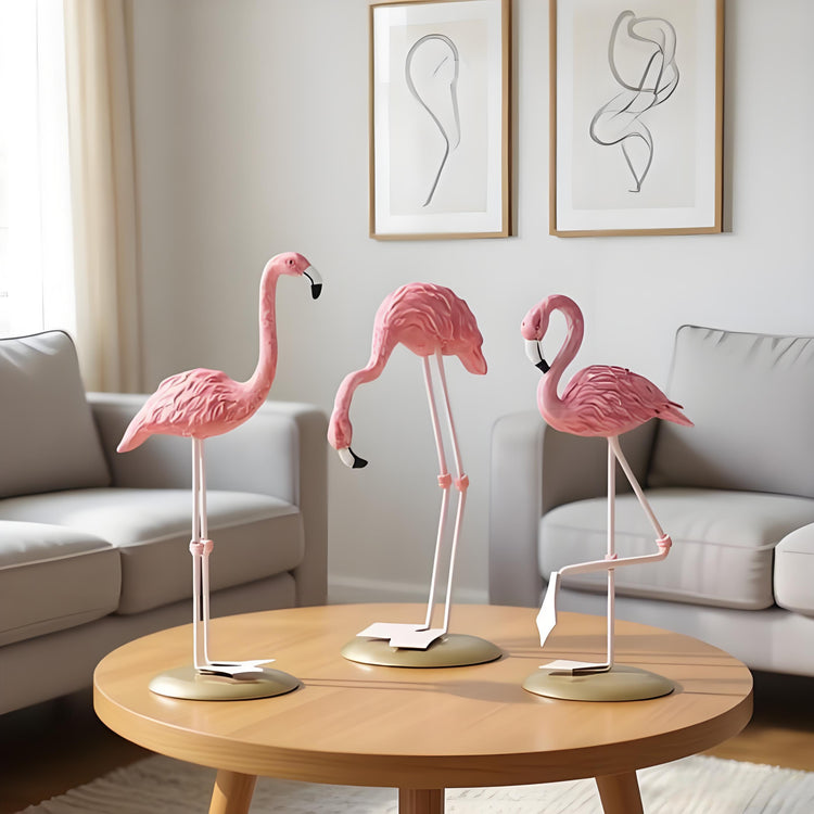 Three pink flamingo ornaments with gold-coloured stands on a coffee table.