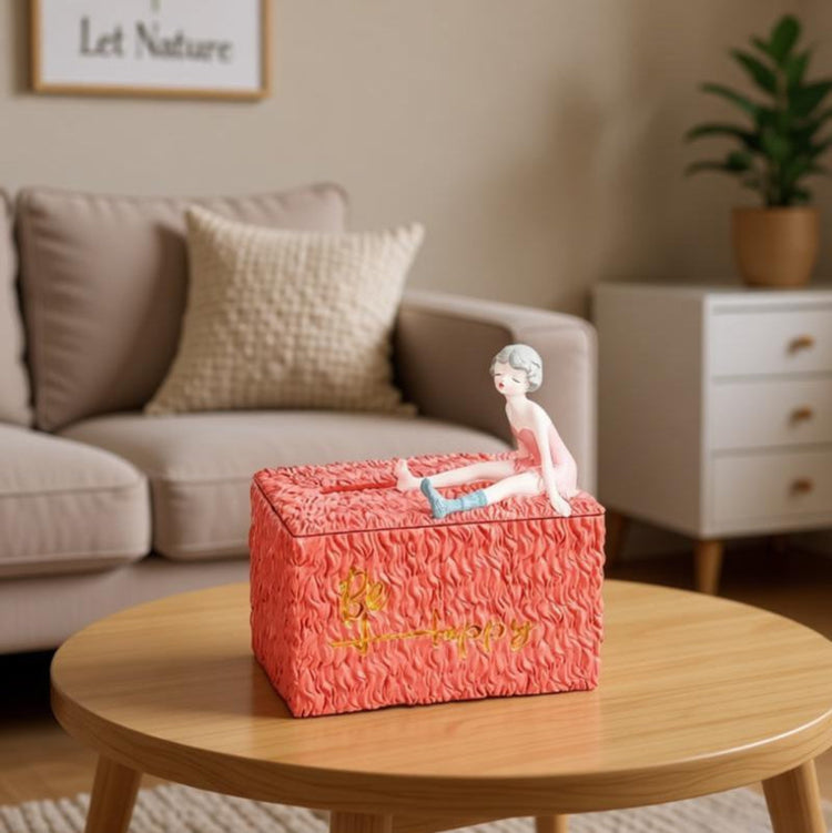 Coral textured tissue box decorated with a reclining girl figurine.
