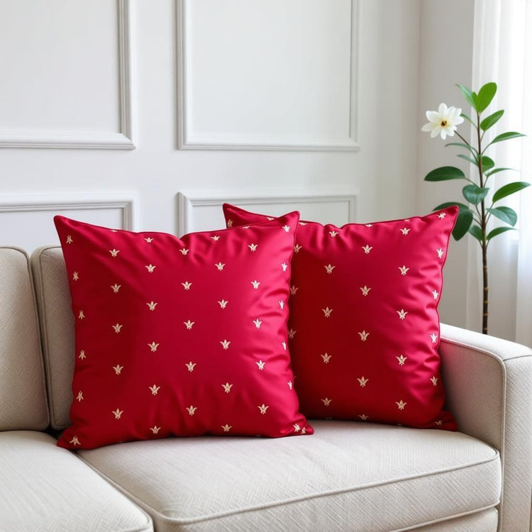 Two red cushion covers with small gold coloured motifs on a cream armchair.