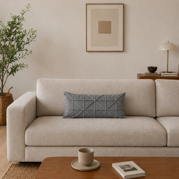 Rectangular silver grey filled cushion with intersecting geometric stitching on a cream sofa.