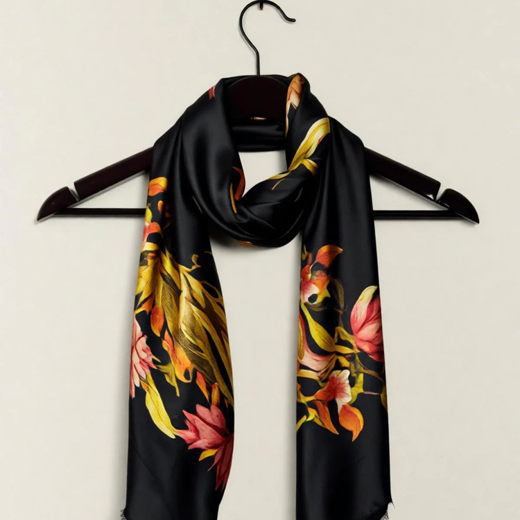 Black floral scarf with orange flowers displayed on a hanger.
