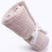 Rolled pale blush cellular blanket tied with a white ribbon.