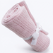 Rolled light pink cellular blanket tied with a white ribbon.