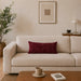 Rectangular burgundy filled cushion with intersecting geometric stitching on a cream sofa.
