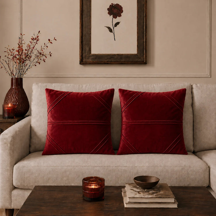 Two red cushion covers with fine horizontal stitched lines on a beige sofa.