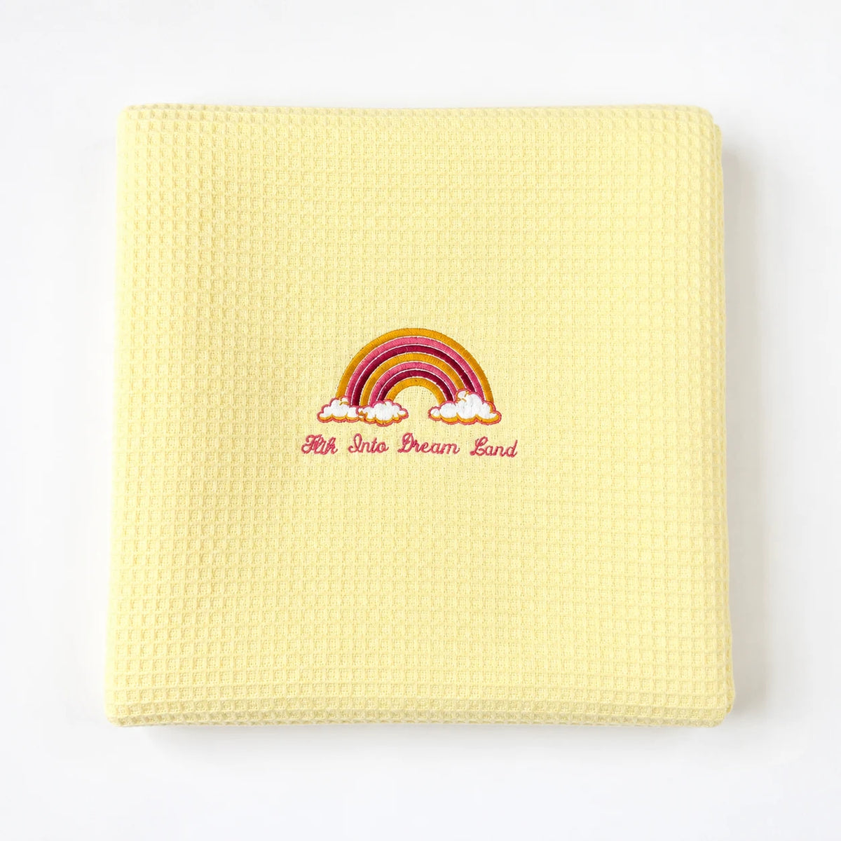 Folded pale yellow waffle-weave baby blanket with a rainbow motif.