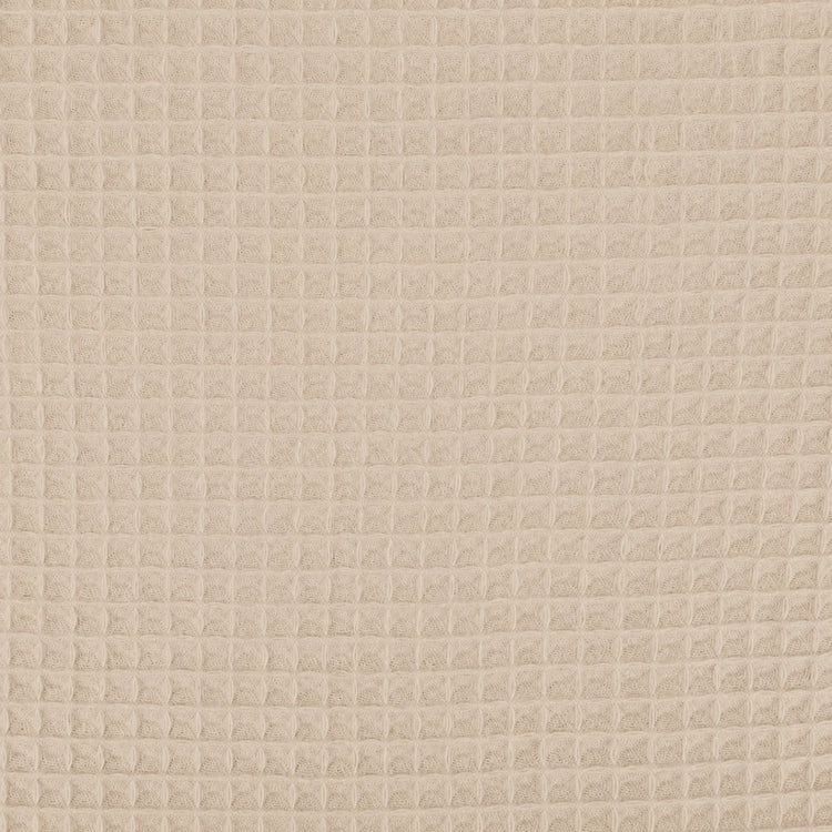 Close-up of the beige grid texture of a cotton thermal blanket.