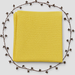 Folded yellow baby blanket with a waffle texture and plain border, surrounded by decorative berry branches.