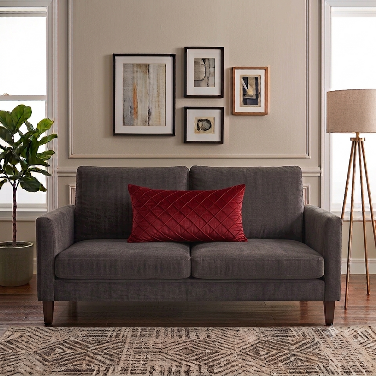 Rectangular red filled cushion with diamond stitching on a dark grey sofa.
