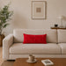 Rectangular red filled cushion with intersecting geometric stitching on a cream sofa.