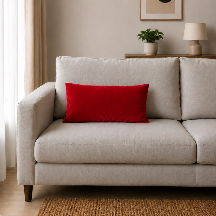 Plain rectangular red filled cushion on a pale sofa.