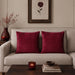 Two burgundy cushion covers with fine horizontal stitched lines on a beige sofa.