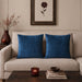 Two blue cushion covers with fine horizontal stitched lines on a beige sofa.