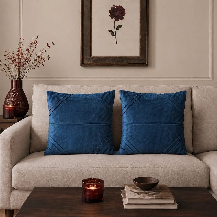 Two blue cushion covers with fine horizontal stitched lines on a beige sofa.