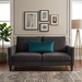 Rectangular teal filled cushion with diamond stitching on a dark grey sofa.