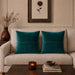 Two teal cushion covers with fine horizontal stitched lines on a beige sofa.