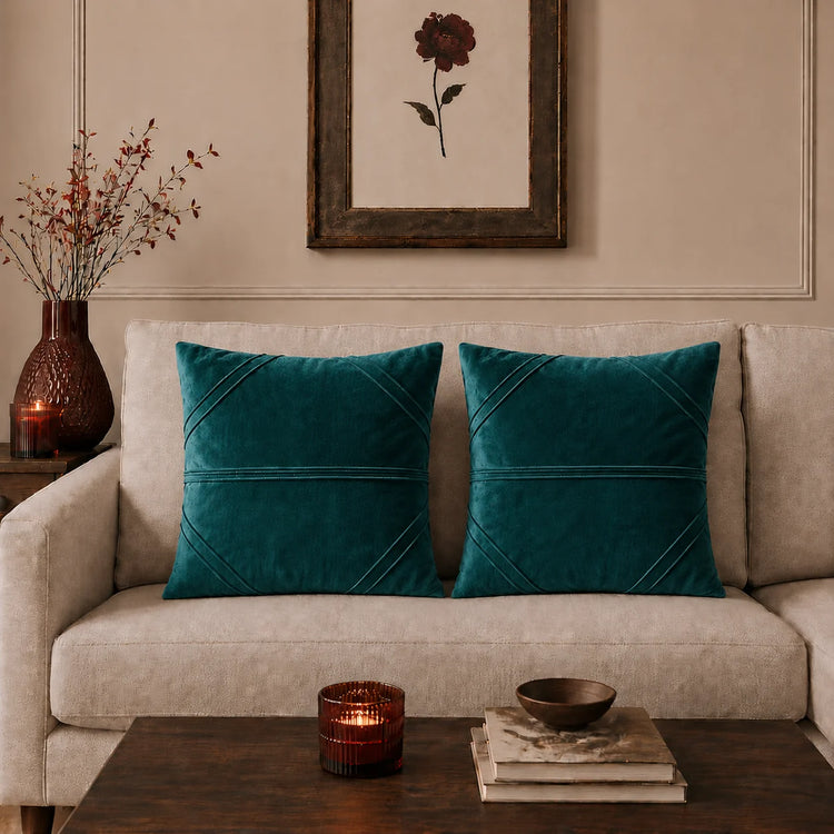 Two teal cushion covers with fine horizontal stitched lines on a beige sofa.