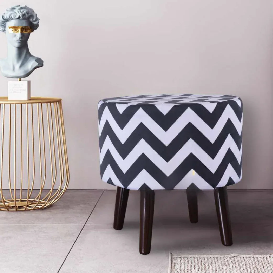 Round upholstered ottoman with a black and white chevron pattern and tapered dark legs.