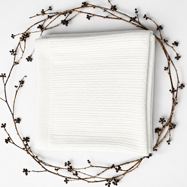 Folded white ribbed blanket framed by decorative dried branches.
