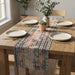 Striped table runner with rust, black and cream geometric patterns on a wooden dining table.