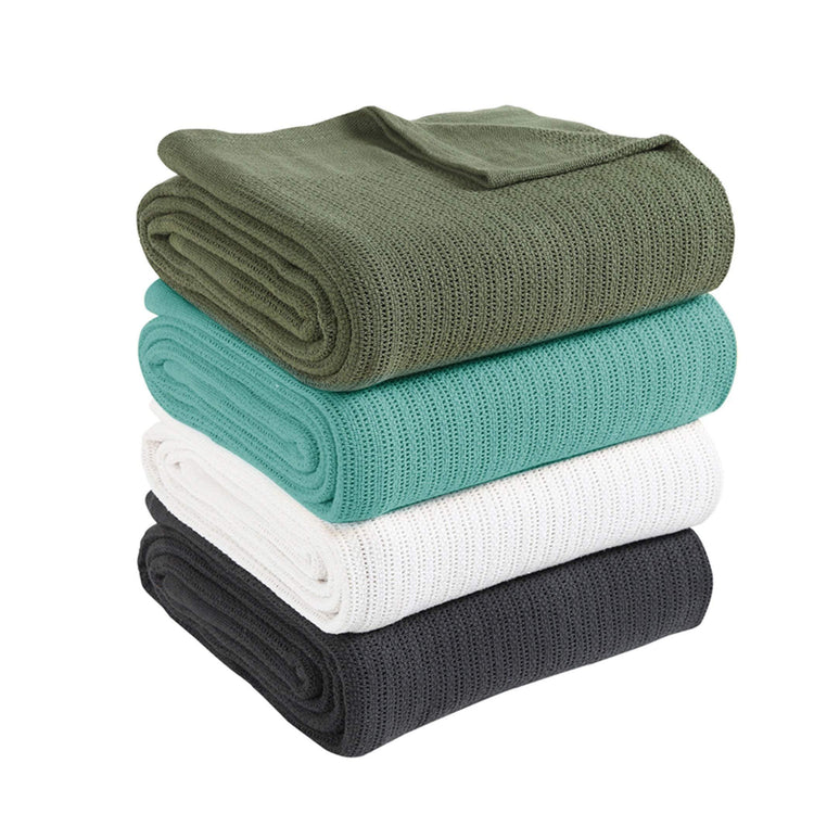Stack of ribbed cotton thermal blankets in green, turquoise, white and charcoal.