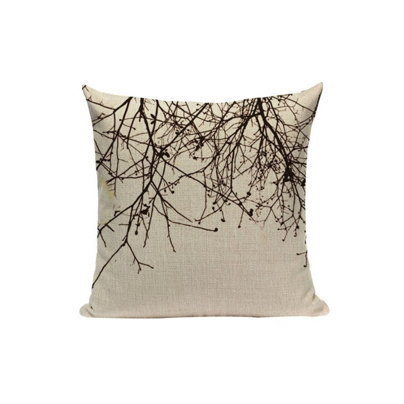 Cream cushion cover with black branches hanging from the top edge.