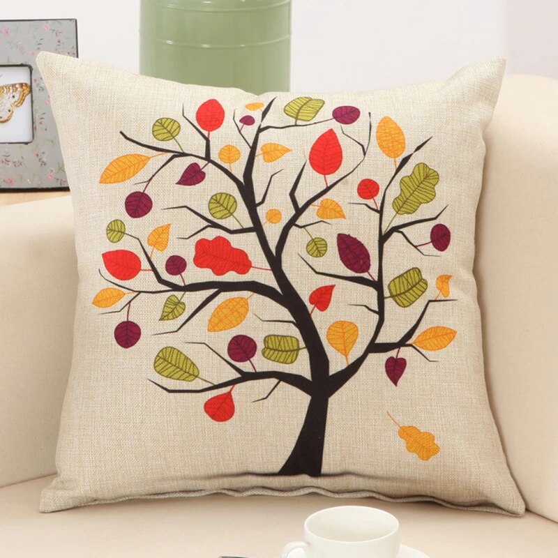 Cream cushion cover with a dark tree and multicoloured leaves.