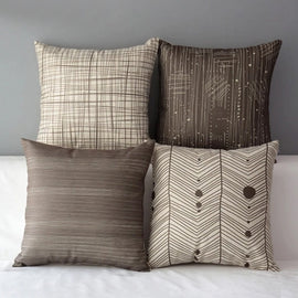 Four grey and cream cushion covers with checked, striped and heart-patterned designs.
