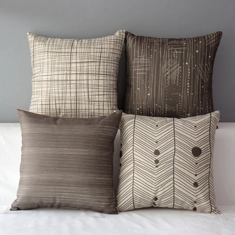 Four grey and cream cushion covers with checked, striped and heart-patterned designs.