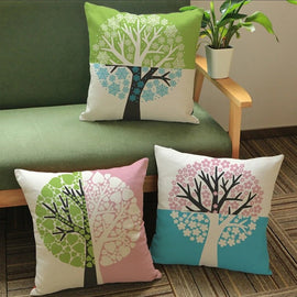 Three pastel cushion covers with round tree designs displayed on chairs and floor.