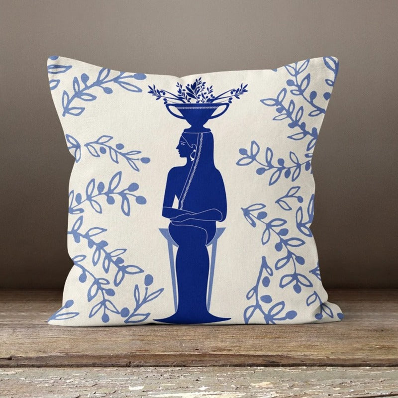 Cream cushion cover with a blue figure carrying a basket among leafy branches.
