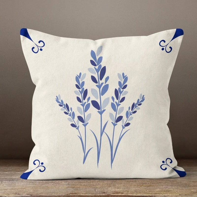 Cream cushion cover with blue leafy stems and small corner flourishes.