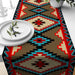 Red, turquoise and beige geometric table runner with diamond motifs.